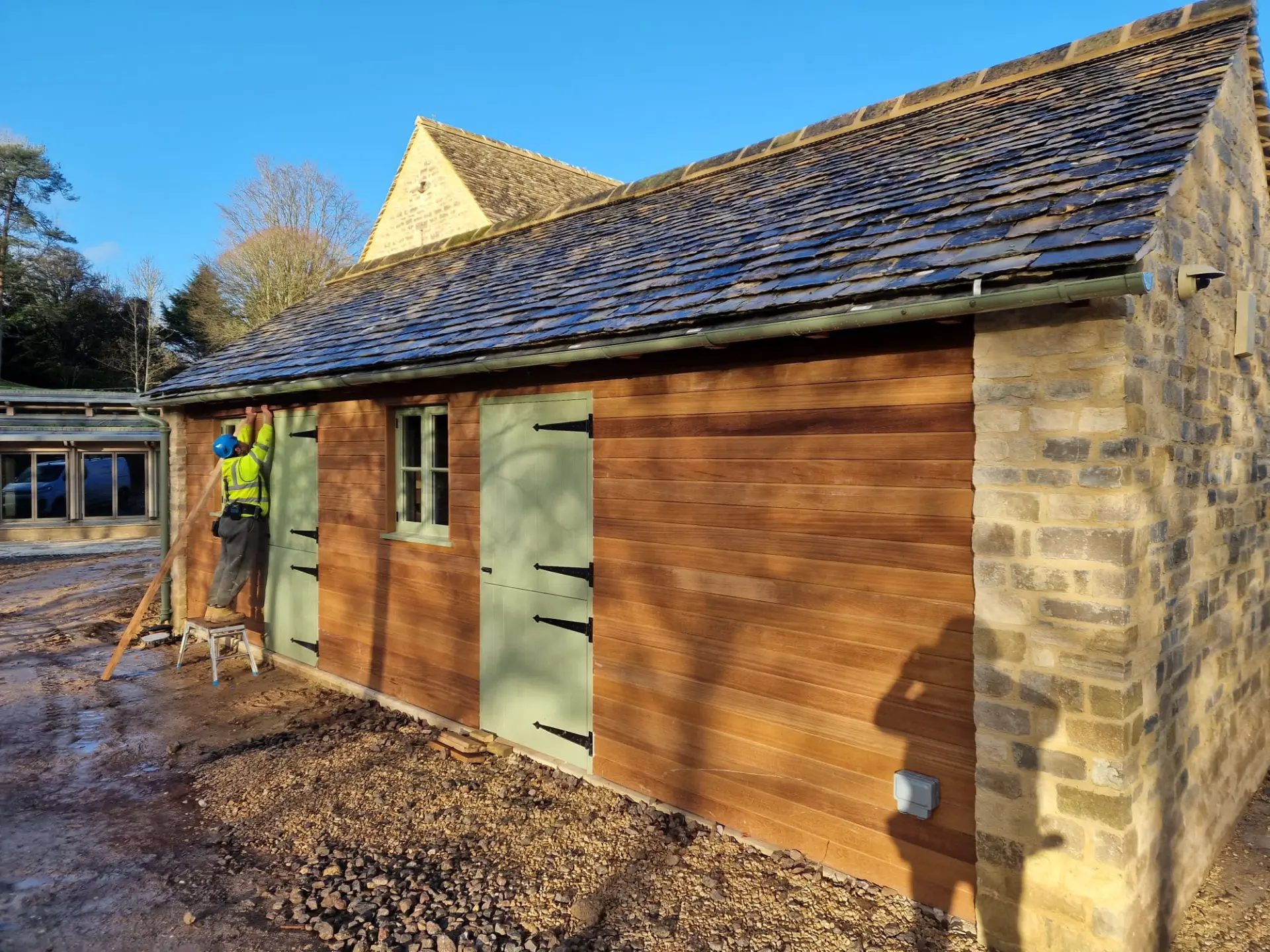ARA Construction craftsman fitting timber cladding to a stone outbuilding